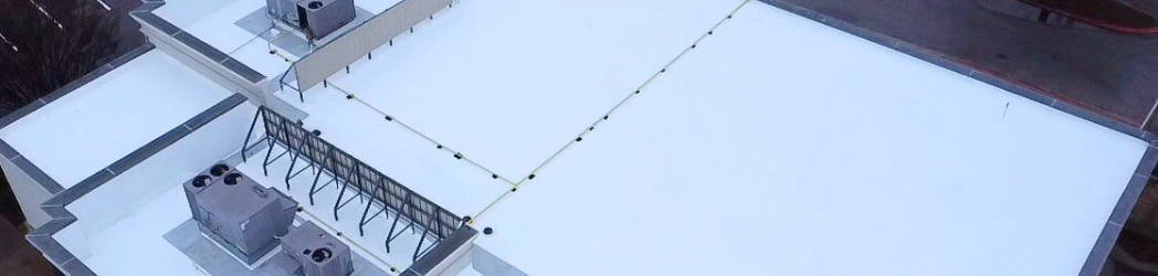 Image is of an aerial view of a fully restored retail property roof, in a high-traffic setting.