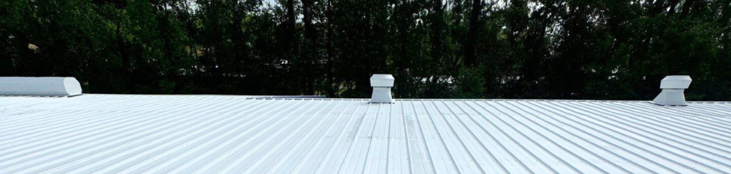 The image is of a pharmacy's metal roof, restored with a fluid-applied acrylic system by the White Hat Industrial team.