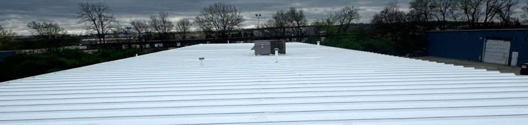 The image is of a metal roof at a pharmacy restored by the White Hat Industrial team with a fluid-applied acrylic solution.