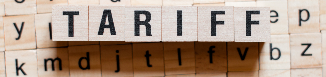 The image is of wooden squares with letters on them. Six of the squares are laid together in the front to spell, "Tariff."