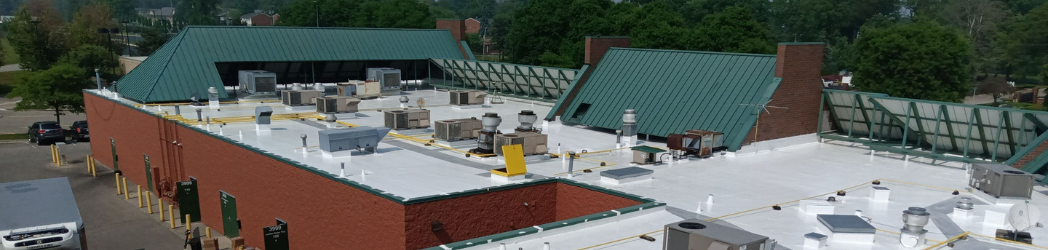 The image shows a strip mall roof restored with a silicone solution.